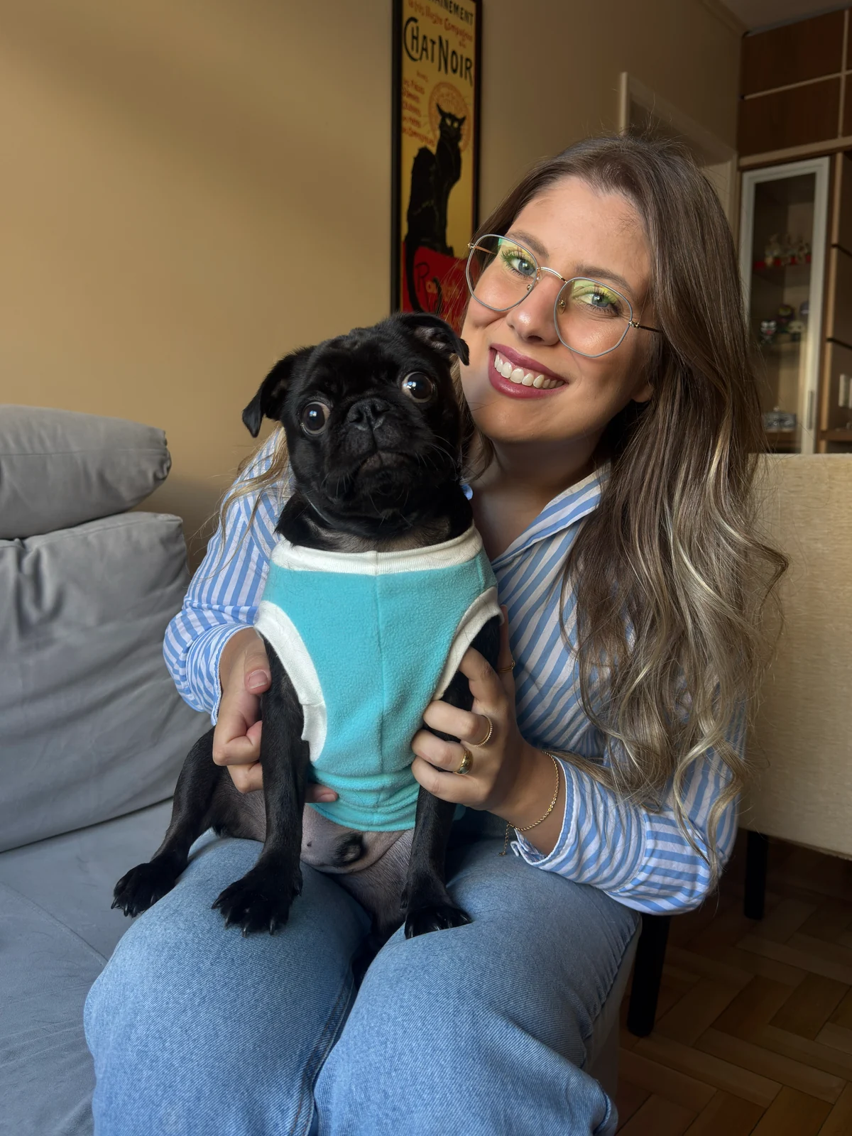 Ratiba Baja sorrindo com um cão preto no colo