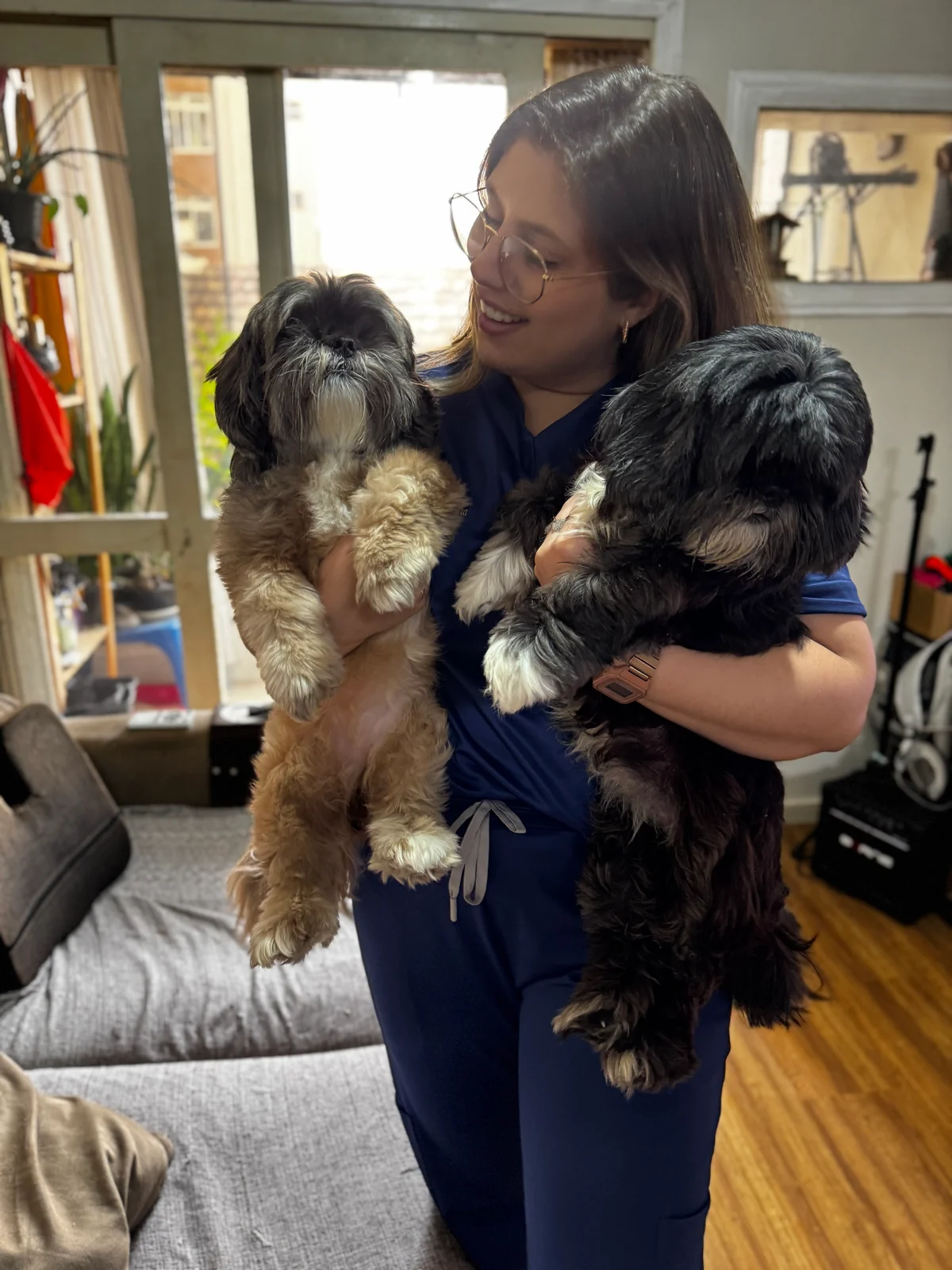 Ratiba Baja segurando dois cães pequenos durante um encontro em casa